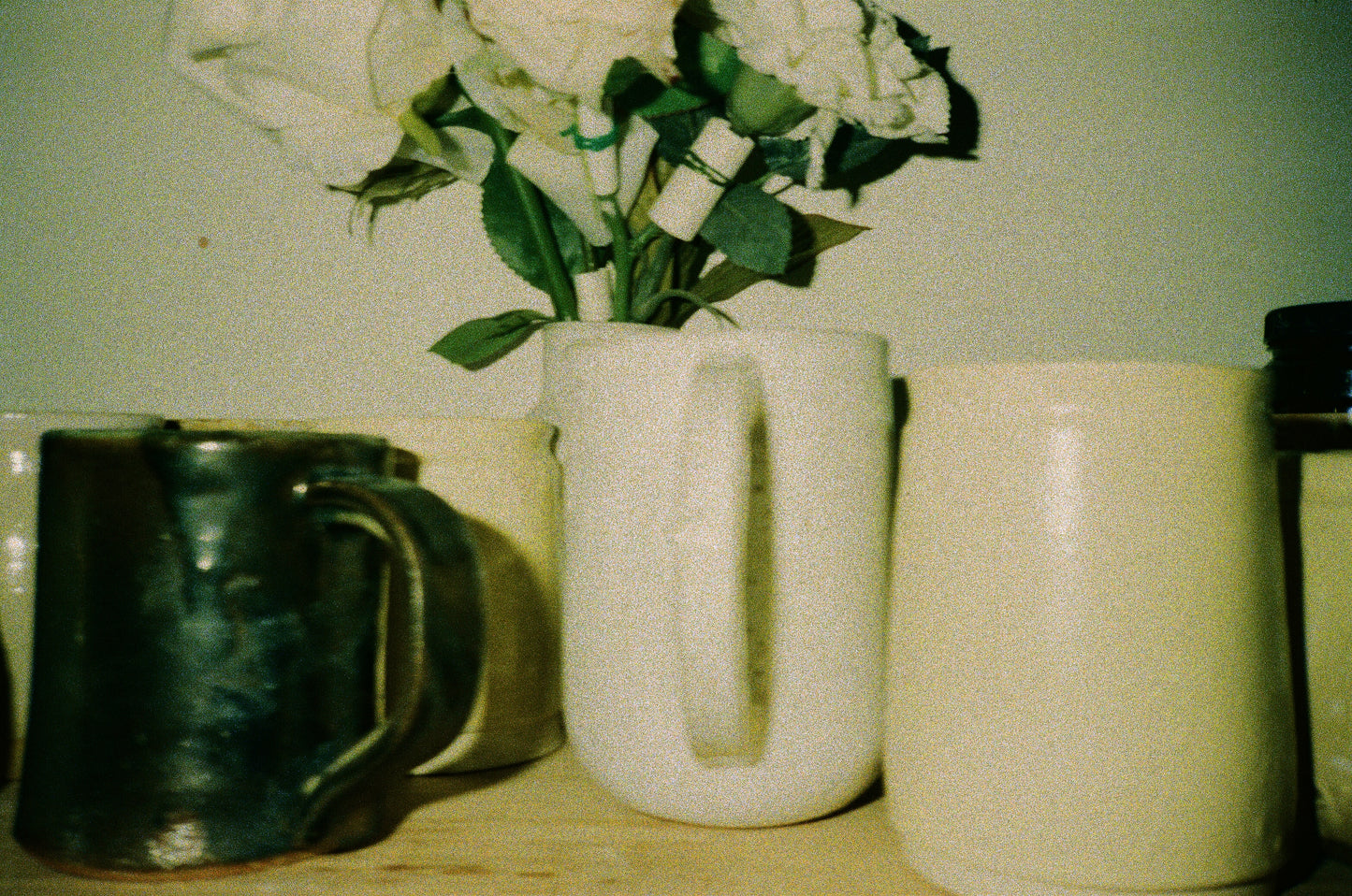 Grainy film photo of a collection of mugs.